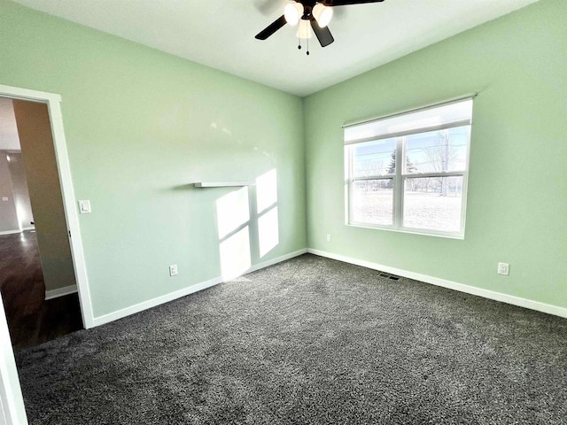 spare room with visible vents, dark carpet, baseboards, and ceiling fan