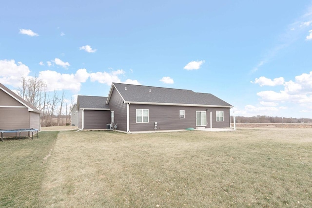 back of property featuring a trampoline, a patio area, and a lawn