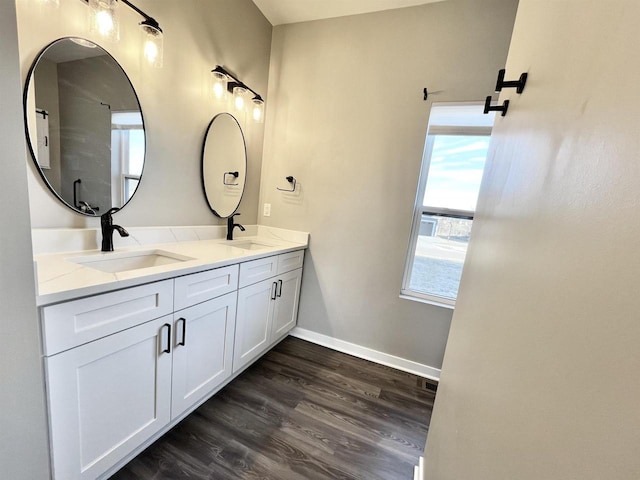 full bathroom with double vanity, baseboards, a sink, and wood finished floors