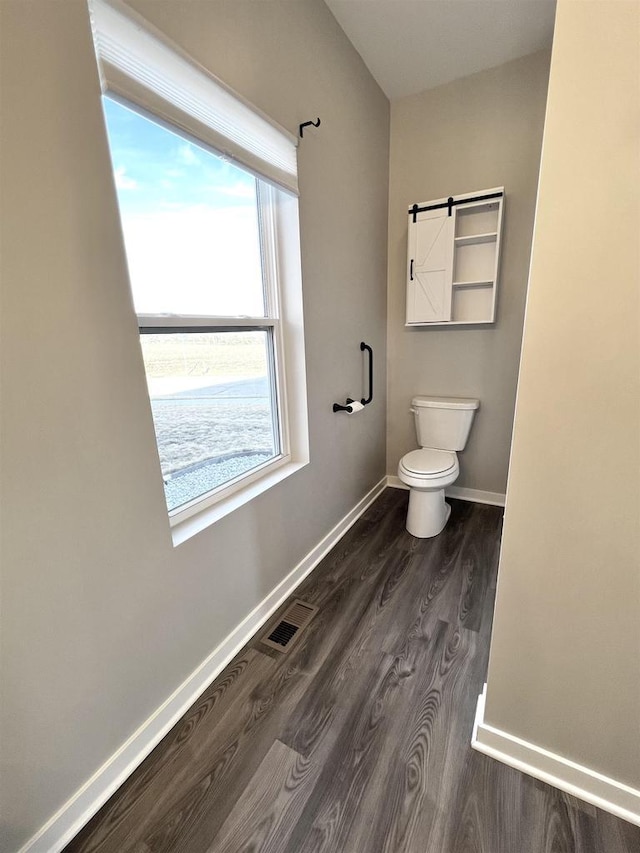 bathroom featuring visible vents, toilet, baseboards, and wood finished floors