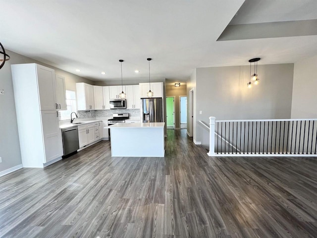 kitchen featuring tasteful backsplash, dark wood-style flooring, stainless steel appliances, light countertops, and a sink