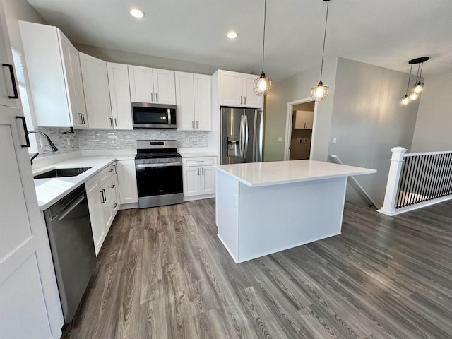 kitchen with appliances with stainless steel finishes, white cabinets, a sink, and decorative backsplash