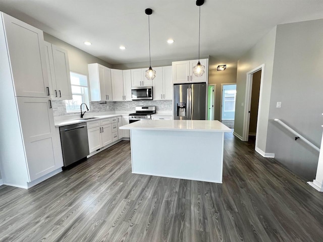 kitchen featuring dark wood-style flooring, stainless steel appliances, tasteful backsplash, white cabinetry, and a sink