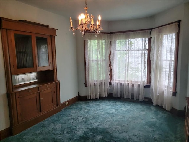 unfurnished dining area featuring carpet floors, baseboards, and a chandelier