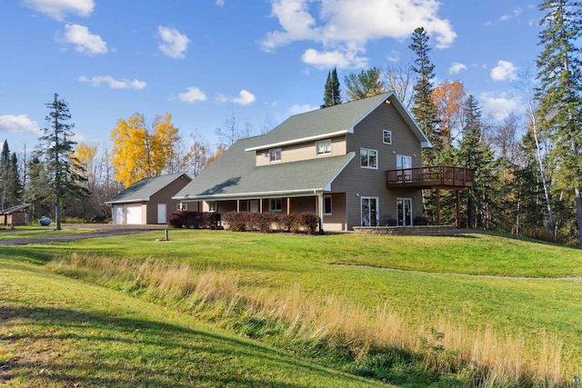 view of front of house with an outbuilding, an attached garage, a deck, and a front lawn