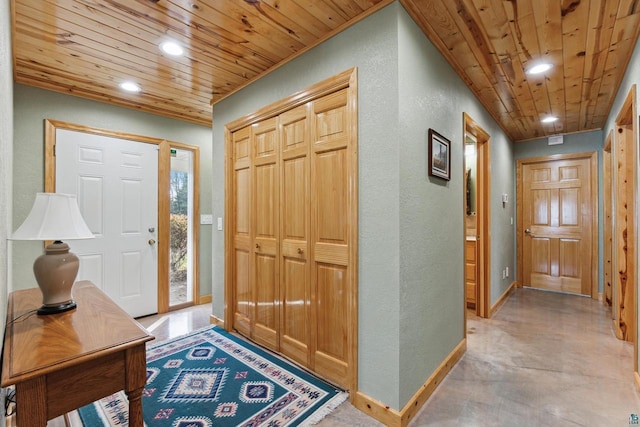 entryway featuring finished concrete flooring, baseboards, a textured wall, wooden ceiling, and recessed lighting