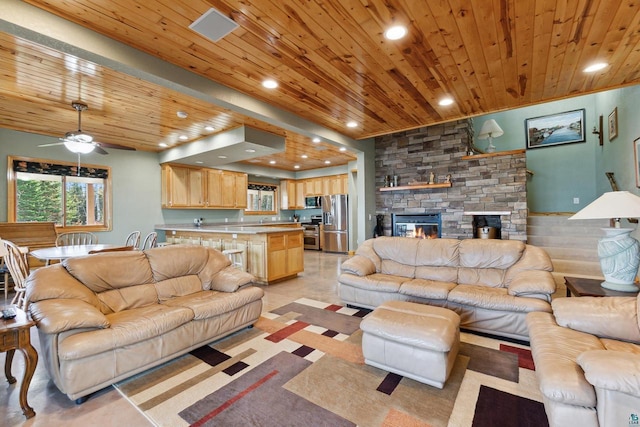 living room with wooden ceiling, ceiling fan, a stone fireplace, and recessed lighting