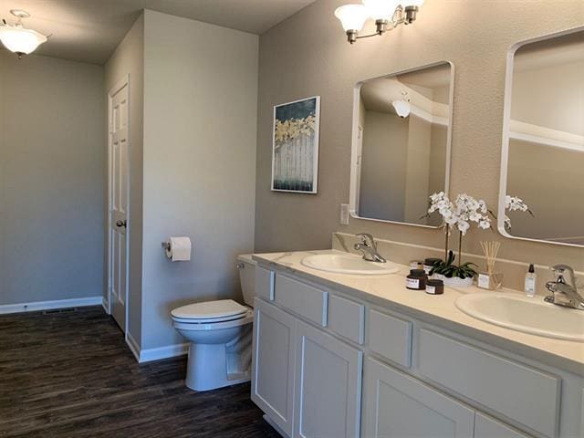 full bathroom with double vanity, wood finished floors, a sink, and toilet