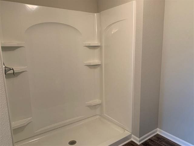 bathroom with a shower, baseboards, and wood finished floors