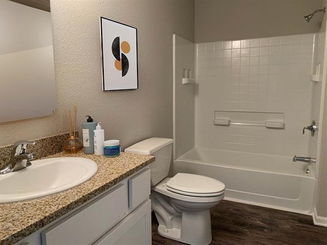 full bath featuring washtub / shower combination, vanity, toilet, and wood finished floors