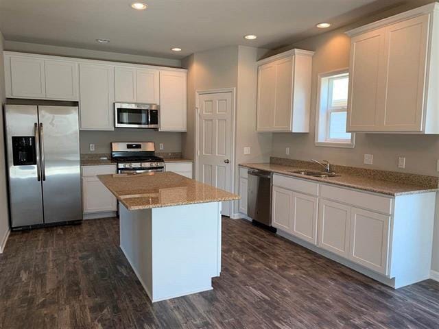 kitchen featuring a sink, white cabinets, appliances with stainless steel finishes, a center island, and dark wood finished floors