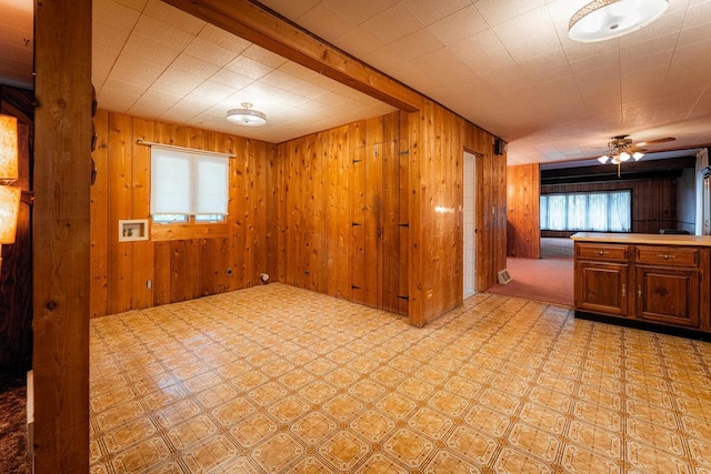 interior space with light floors, wooden walls, and a ceiling fan