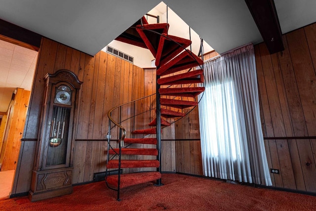 stairs featuring carpet, visible vents, and wooden walls