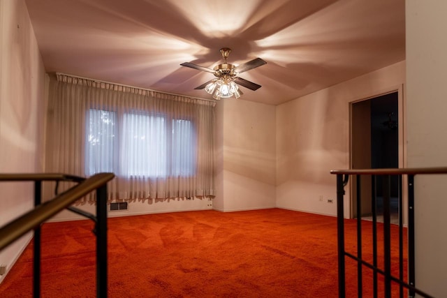 carpeted empty room featuring a ceiling fan, visible vents, and baseboards