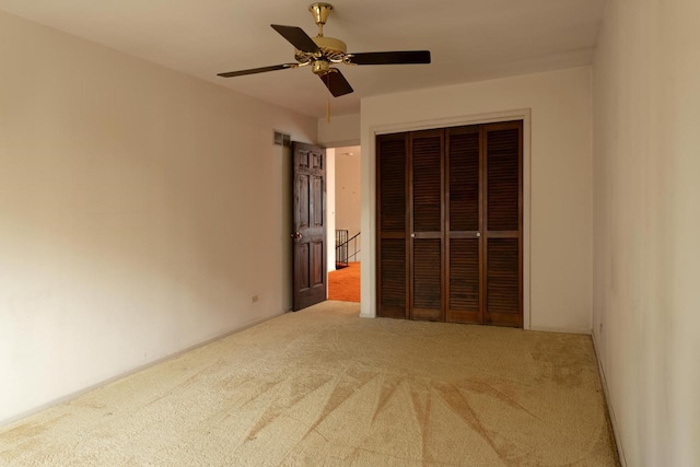 unfurnished bedroom featuring carpet floors, a closet, visible vents, and a ceiling fan