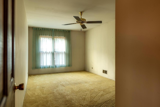 carpeted empty room featuring ceiling fan and visible vents