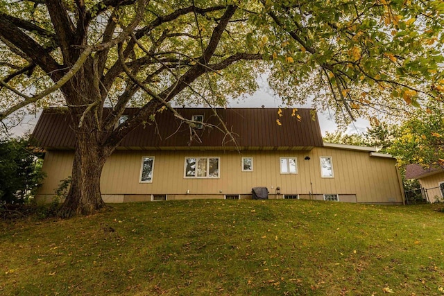 rear view of house featuring metal roof and a yard