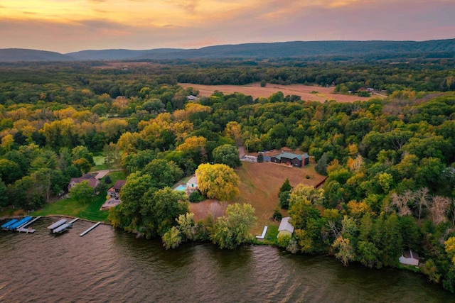 aerial view at dusk featuring a forest view and a water and mountain view