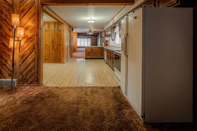 kitchen with light carpet, wooden walls, visible vents, range, and white fridge with ice dispenser