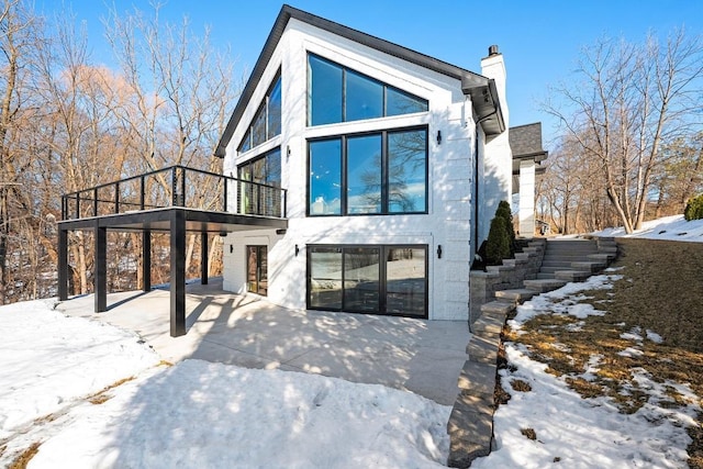 contemporary home featuring a patio, stairway, and a chimney