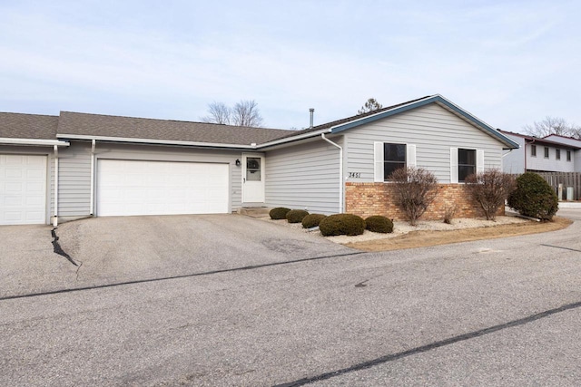 view of front of property with a garage, driveway, a shingled roof, and brick siding