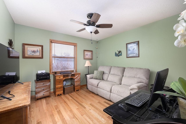 living area with a ceiling fan, a textured ceiling, and light wood finished floors