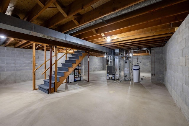 unfinished below grade area featuring water heater, stairs, and heating unit