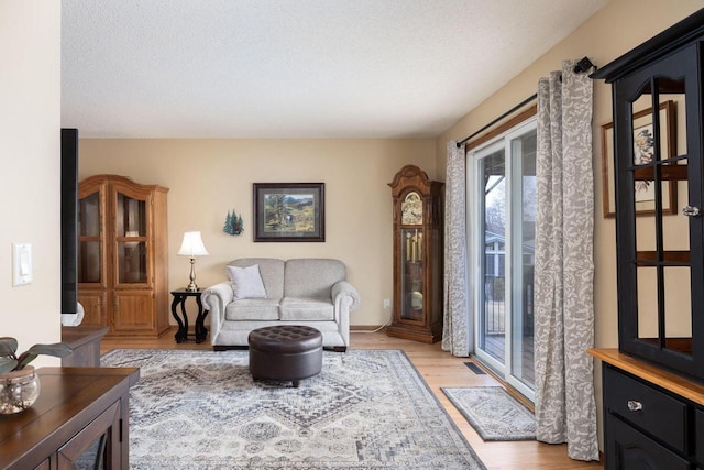 living area featuring a textured ceiling, light wood finished floors, and visible vents