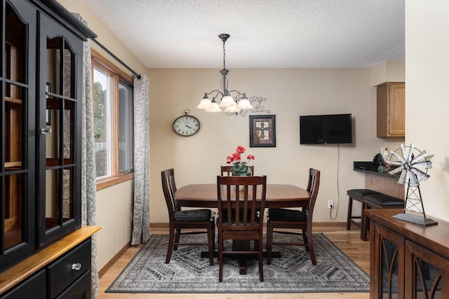 dining space with a textured ceiling, light wood-type flooring, a chandelier, and baseboards