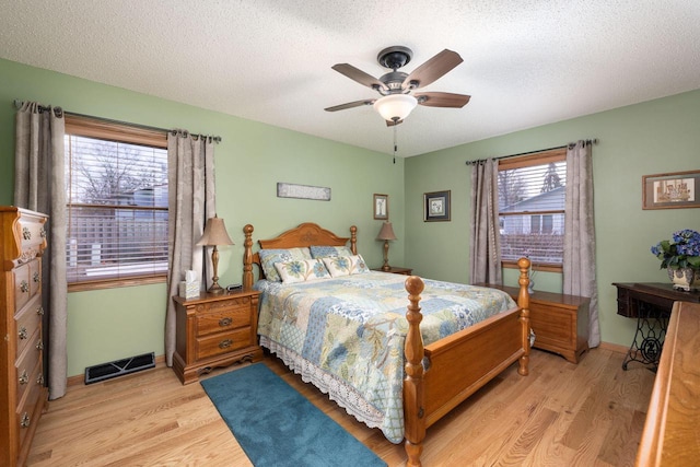 bedroom featuring a textured ceiling, light wood-type flooring, visible vents, and baseboards