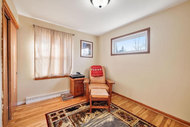 living area with light wood-type flooring, baseboards, and baseboard heating