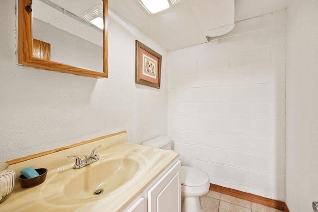 half bath with tile patterned floors, toilet, and vanity