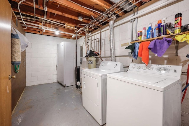 washroom featuring washer and dryer, laundry area, concrete block wall, and water heater