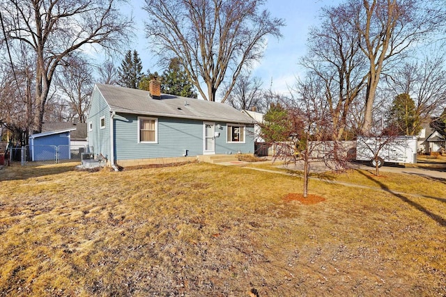 back of property with a yard, a chimney, and fence