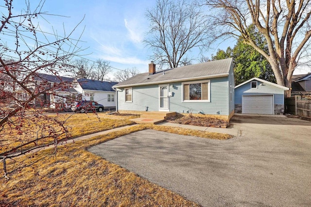 view of front of property featuring fence, a chimney, a garage, an outbuilding, and driveway