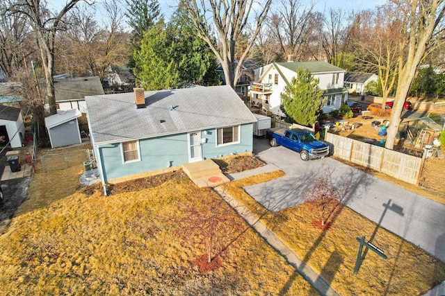 view of front facade featuring aphalt driveway, a tiled roof, fence, and a chimney