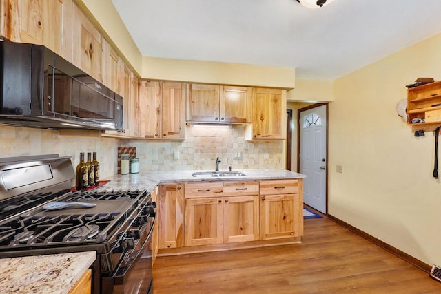 kitchen featuring backsplash, black microwave, gas range, light wood-style flooring, and a sink