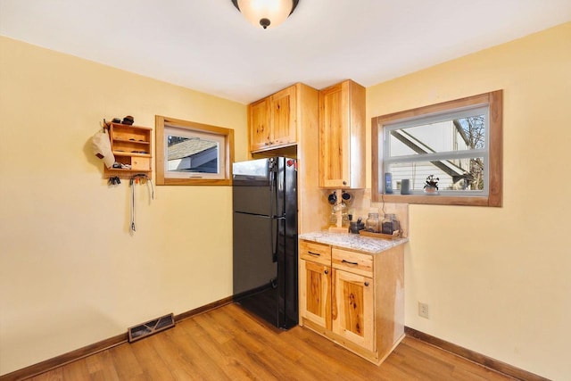 kitchen featuring light wood finished floors, visible vents, freestanding refrigerator, and baseboards