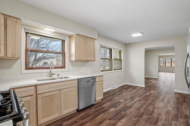 kitchen with light brown cabinets, dark wood-type flooring, a sink, dishwasher, and gas range