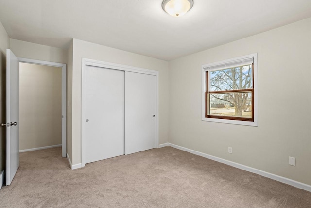 unfurnished bedroom with baseboards, a closet, and light colored carpet