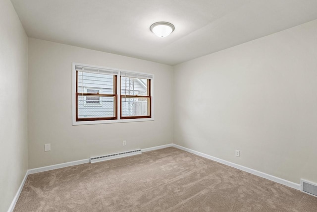 empty room with a baseboard heating unit, carpet, visible vents, and baseboards