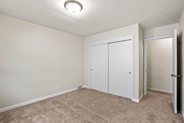 unfurnished bedroom featuring carpet floors, a closet, visible vents, and baseboards