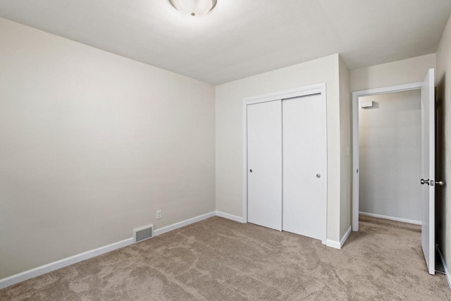 unfurnished bedroom with a closet, carpet, visible vents, and baseboards