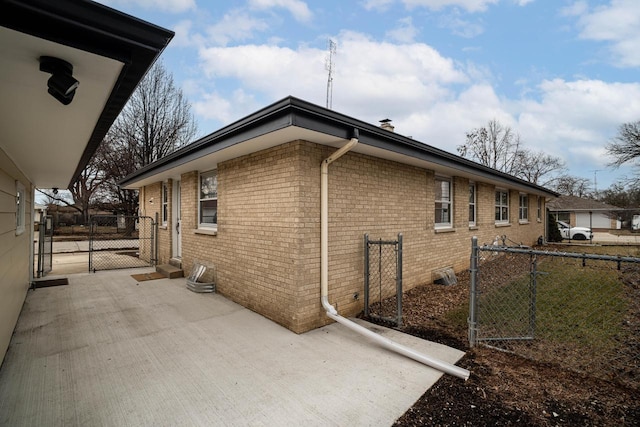 view of side of home with brick siding, fence, and a gate