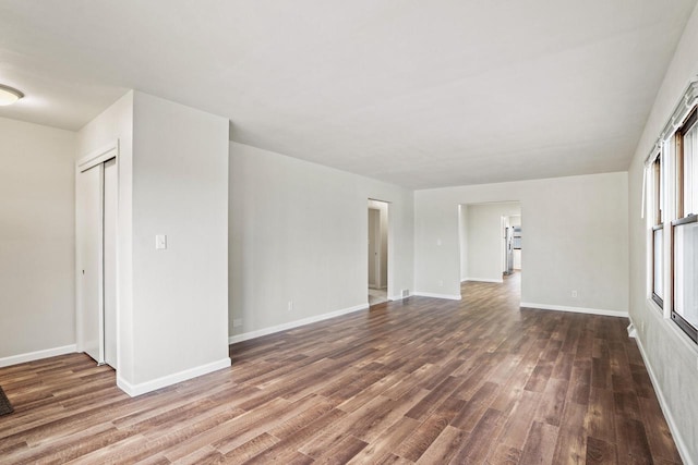 empty room with dark wood-style flooring and baseboards