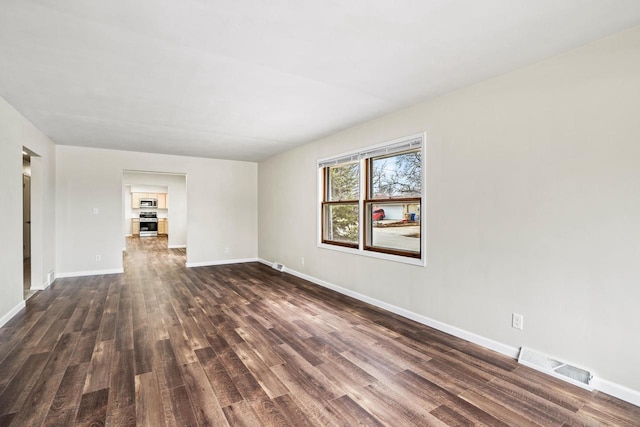 empty room with baseboards, visible vents, and dark wood-style flooring