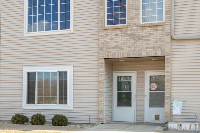 entrance to property featuring visible vents and brick siding