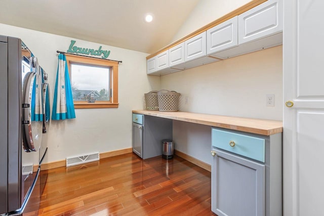 unfurnished office with baseboards, visible vents, lofted ceiling, wood finished floors, and recessed lighting