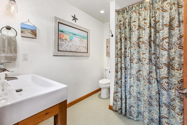 full bathroom featuring a shower with shower curtain, a sink, toilet, and baseboards