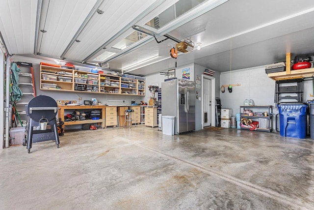 garage with a garage door opener, a workshop area, and stainless steel fridge with ice dispenser